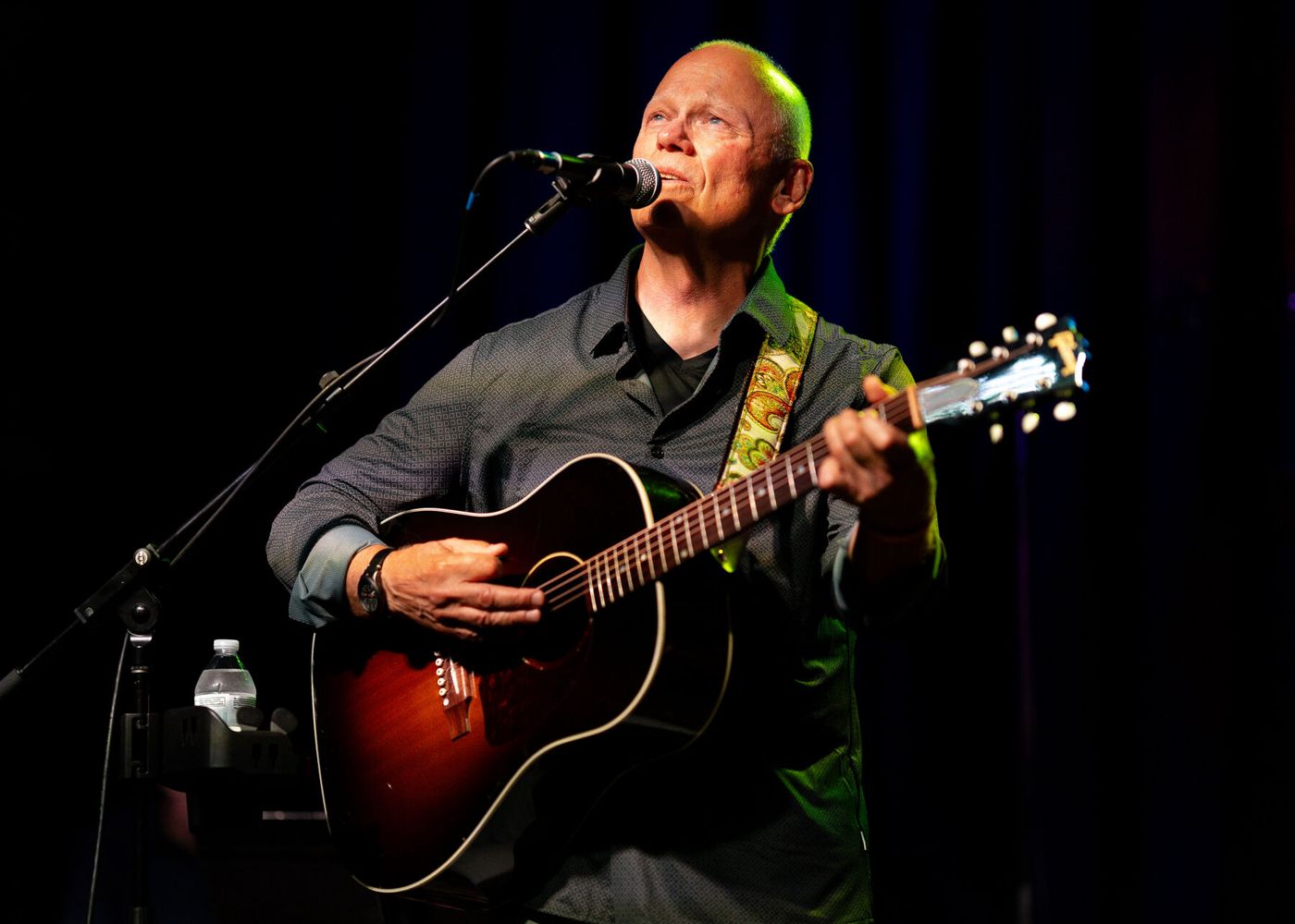 Dennis O'Brien singing and playing acoustic guitar on stage with Laurel Canyon Collective